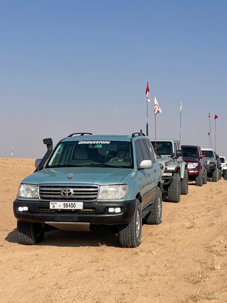 Toyota Land Cruiser leading a desert convoy of 4x4s with club safety flags